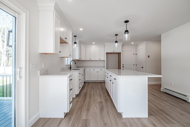 kitchen with baseboard heating, white cabinetry, plenty of natural light, and hanging light fixtures