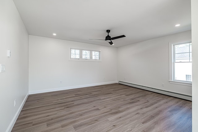 empty room with ceiling fan, baseboard heating, and light wood-type flooring