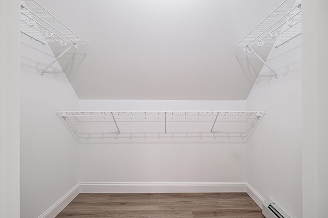 spacious closet with a baseboard radiator and hardwood / wood-style floors