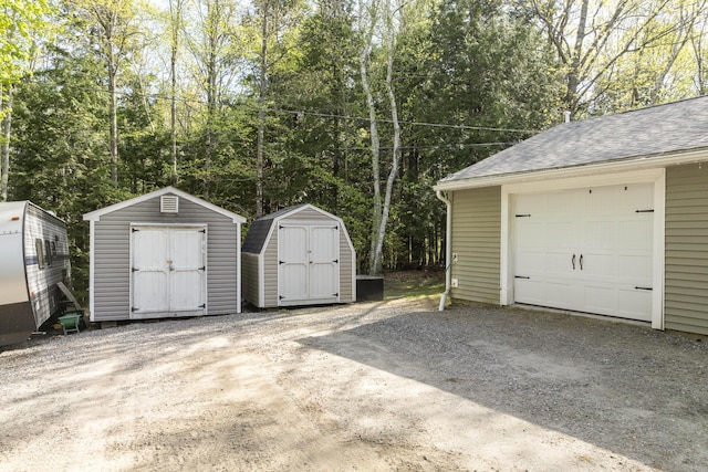 16 Hayden Hill Rd, Litchfield, ME 04350 - garage featuring a storage unit, driveway, and view of wooded area