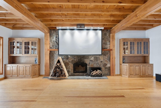 unfurnished living room with wood ceiling, light wood-type flooring, beamed ceiling, and a stone fireplace