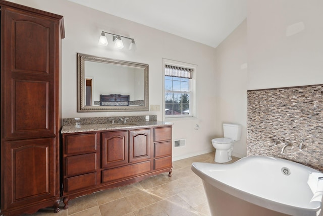 bathroom with lofted ceiling, tile patterned floors, vanity, a bathtub, and toilet