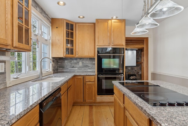 kitchen featuring black appliances, decorative light fixtures, decorative backsplash, sink, and light hardwood / wood-style flooring