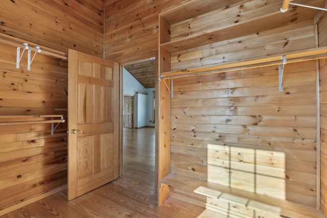 interior space with hardwood / wood-style flooring, wood walls, and vaulted ceiling