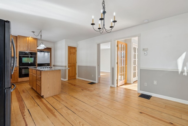 kitchen with pendant lighting, a kitchen island, double oven, light hardwood / wood-style floors, and stainless steel refrigerator