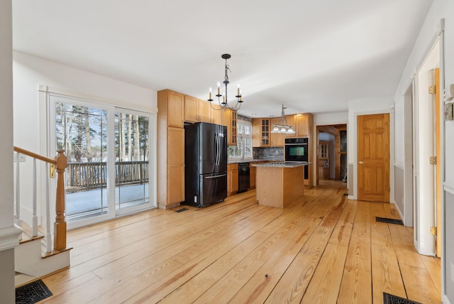 kitchen with pendant lighting, black appliances, a kitchen island, tasteful backsplash, and light hardwood / wood-style flooring