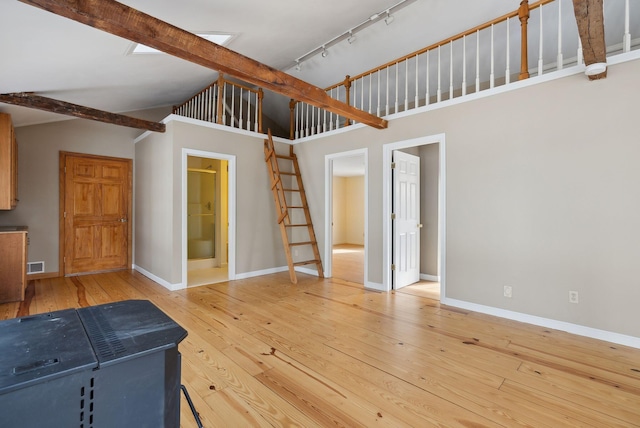 unfurnished living room featuring high vaulted ceiling, hardwood / wood-style floors, track lighting, and beamed ceiling