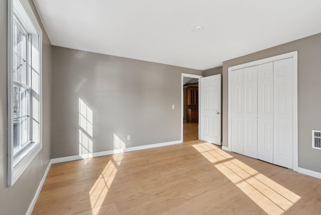 unfurnished bedroom featuring light wood-type flooring and a closet