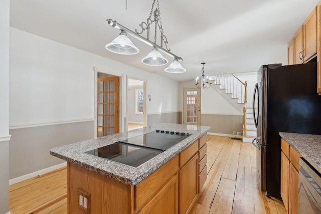 kitchen featuring white dishwasher, decorative light fixtures, black electric stovetop, a kitchen island, and stainless steel refrigerator