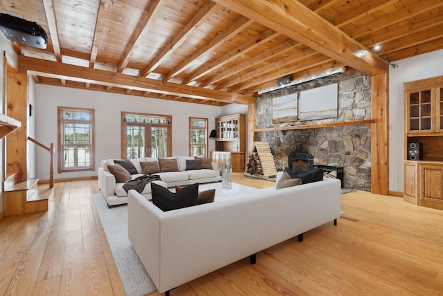 living room featuring beamed ceiling, a fireplace, light hardwood / wood-style floors, and wooden ceiling