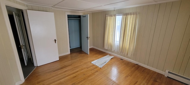 unfurnished bedroom featuring a baseboard heating unit, a closet, and light hardwood / wood-style flooring