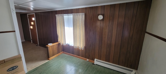 unfurnished room with carpet, a baseboard heating unit, and wooden walls