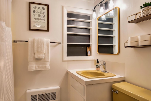 bathroom with toilet, sink, and heating unit