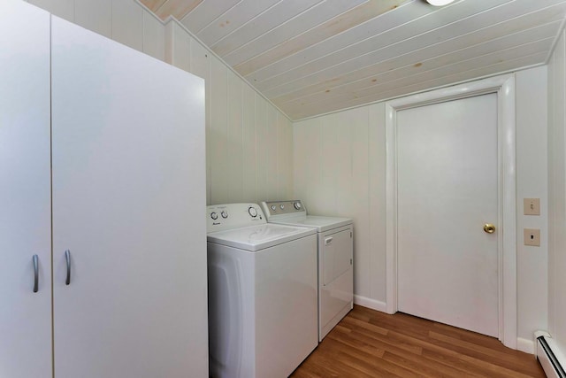 clothes washing area with light hardwood / wood-style floors, wooden walls, washing machine and clothes dryer, baseboard heating, and wooden ceiling