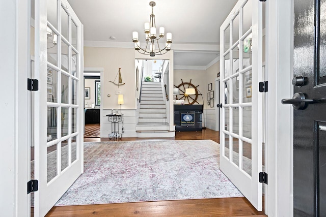 entrance foyer featuring a notable chandelier, dark hardwood / wood-style floors, ornamental molding, and french doors