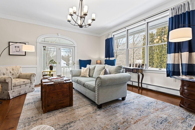 living room featuring wood-type flooring, plenty of natural light, crown molding, and baseboard heating