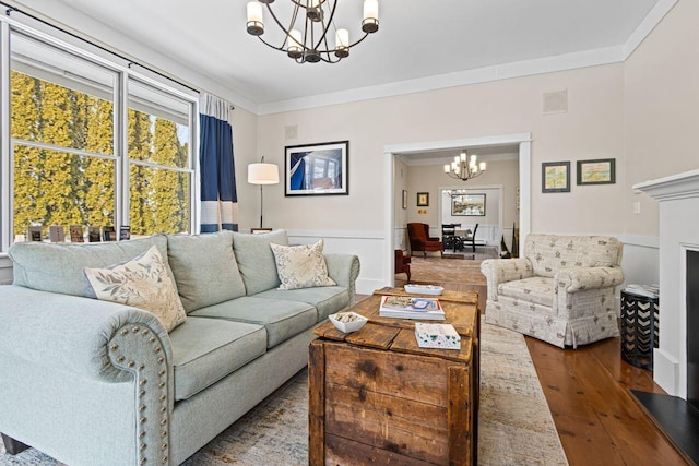 living room featuring hardwood / wood-style flooring, ornamental molding, and a chandelier