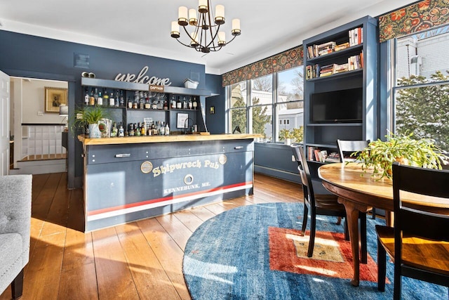 bar with wood-type flooring, decorative light fixtures, and a chandelier