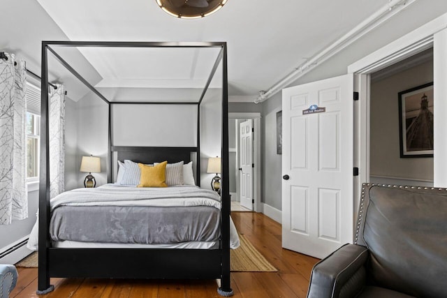 bedroom featuring hardwood / wood-style flooring and a baseboard heating unit