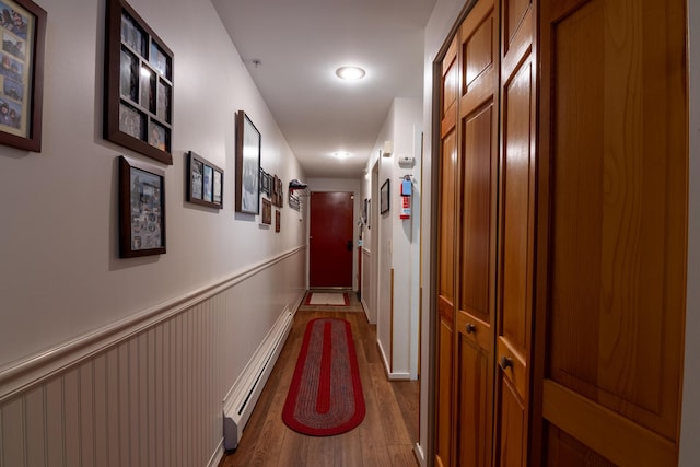 corridor featuring dark wood-type flooring and baseboard heating