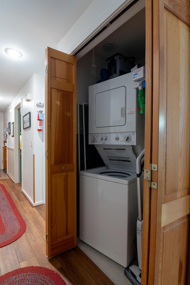 clothes washing area featuring stacked washer / drying machine and light wood-type flooring