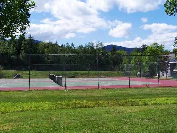 view of sport court featuring a mountain view and a lawn