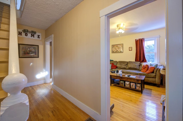 hall featuring light hardwood / wood-style flooring and a textured ceiling