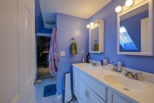 bathroom with tile patterned floors, vanity, a skylight, and a textured ceiling