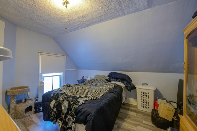 bedroom with hardwood / wood-style flooring, vaulted ceiling, and a textured ceiling