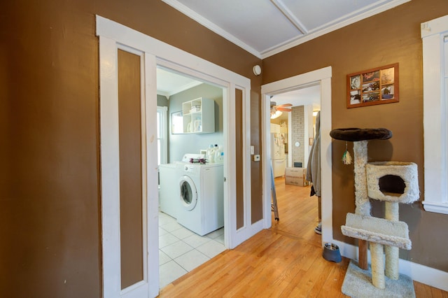 washroom featuring ornamental molding, washer and clothes dryer, and light wood-type flooring