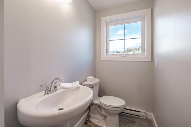 bathroom featuring a baseboard heating unit, toilet, and sink