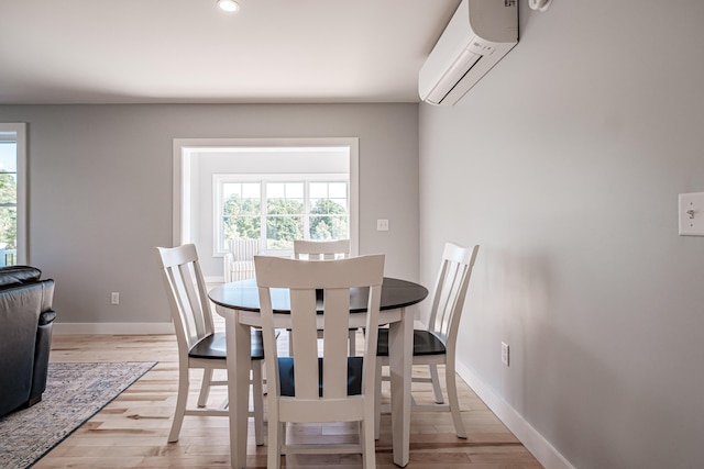 dining area featuring an AC wall unit and light hardwood / wood-style flooring