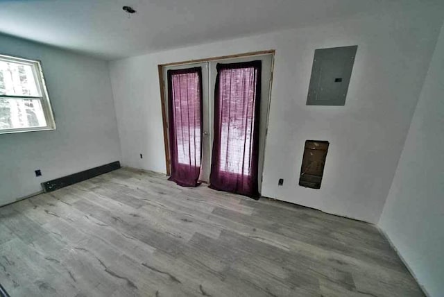 spare room with electric panel and light hardwood / wood-style flooring