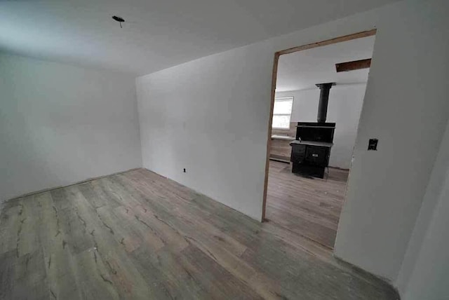 empty room with a wood stove and light hardwood / wood-style flooring