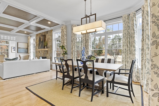 dining space with light hardwood / wood-style floors, a wealth of natural light, beamed ceiling, coffered ceiling, and ornamental molding