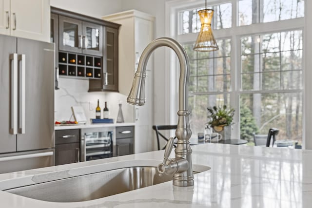 bar with tasteful backsplash, high quality fridge, white cabinetry, light stone countertops, and dark brown cabinets