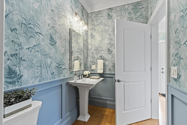 bathroom with toilet, crown molding, and hardwood / wood-style floors