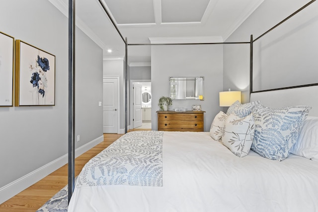 bedroom with ornamental molding, stacked washer / drying machine, hardwood / wood-style flooring, and ensuite bath