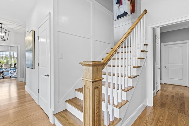 stairway with wood-type flooring and a notable chandelier