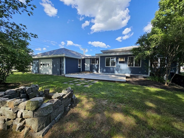 back of property with a deck, a garage, and a yard