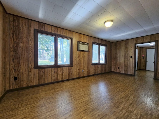 empty room featuring a wall unit AC, dark hardwood / wood-style flooring, and wooden walls