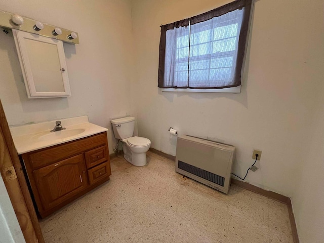 bathroom with heating unit, vanity, and toilet