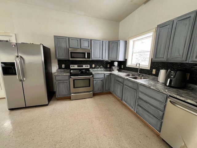 kitchen featuring backsplash, stainless steel appliances, sink, and gray cabinetry