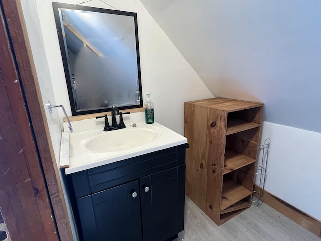 bathroom featuring wood-type flooring, vanity, and vaulted ceiling