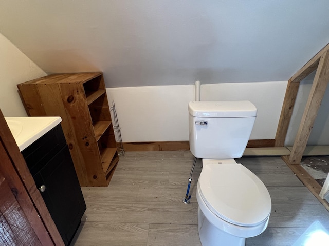 bathroom with toilet, vanity, and vaulted ceiling