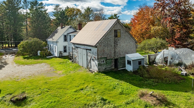 rear view of house featuring an outbuilding and a lawn