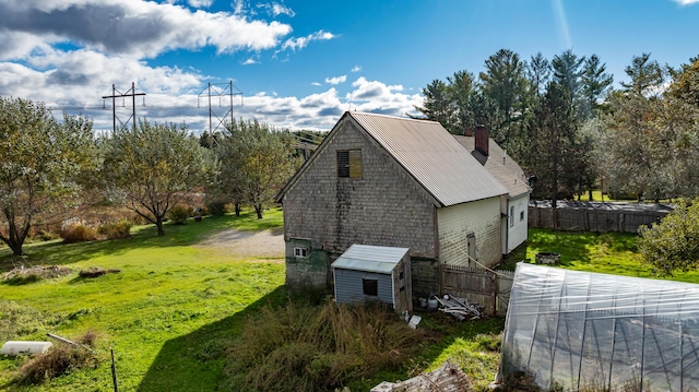 view of side of home with a storage shed and a yard