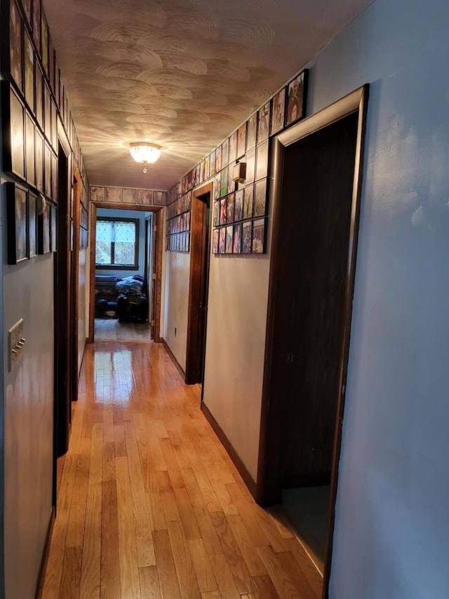 corridor with light wood-type flooring and wood ceiling