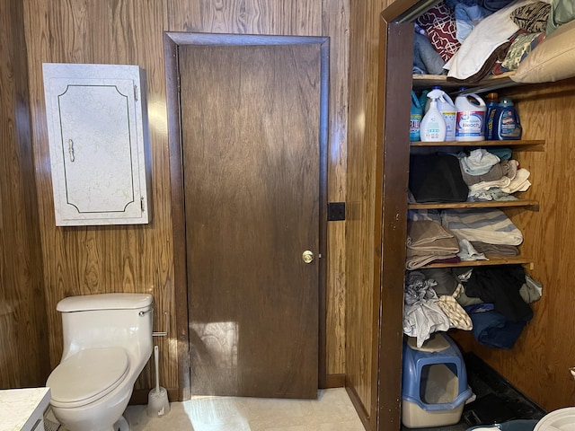 bathroom with toilet, electric panel, and wood walls