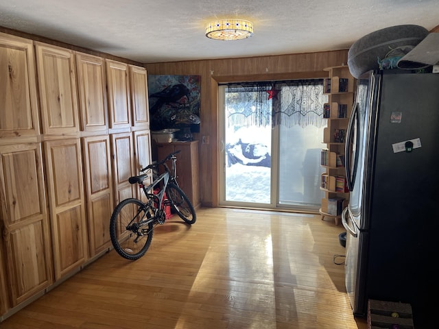 interior space with light hardwood / wood-style floors, a textured ceiling, and wooden walls